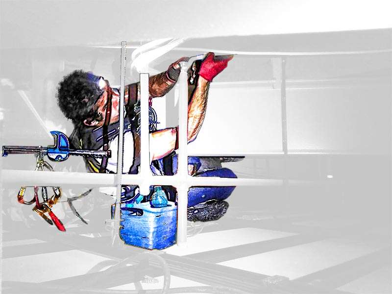 Industriekletterer in einer beengten Zwischendecke beim Wechsel von Sprinklern